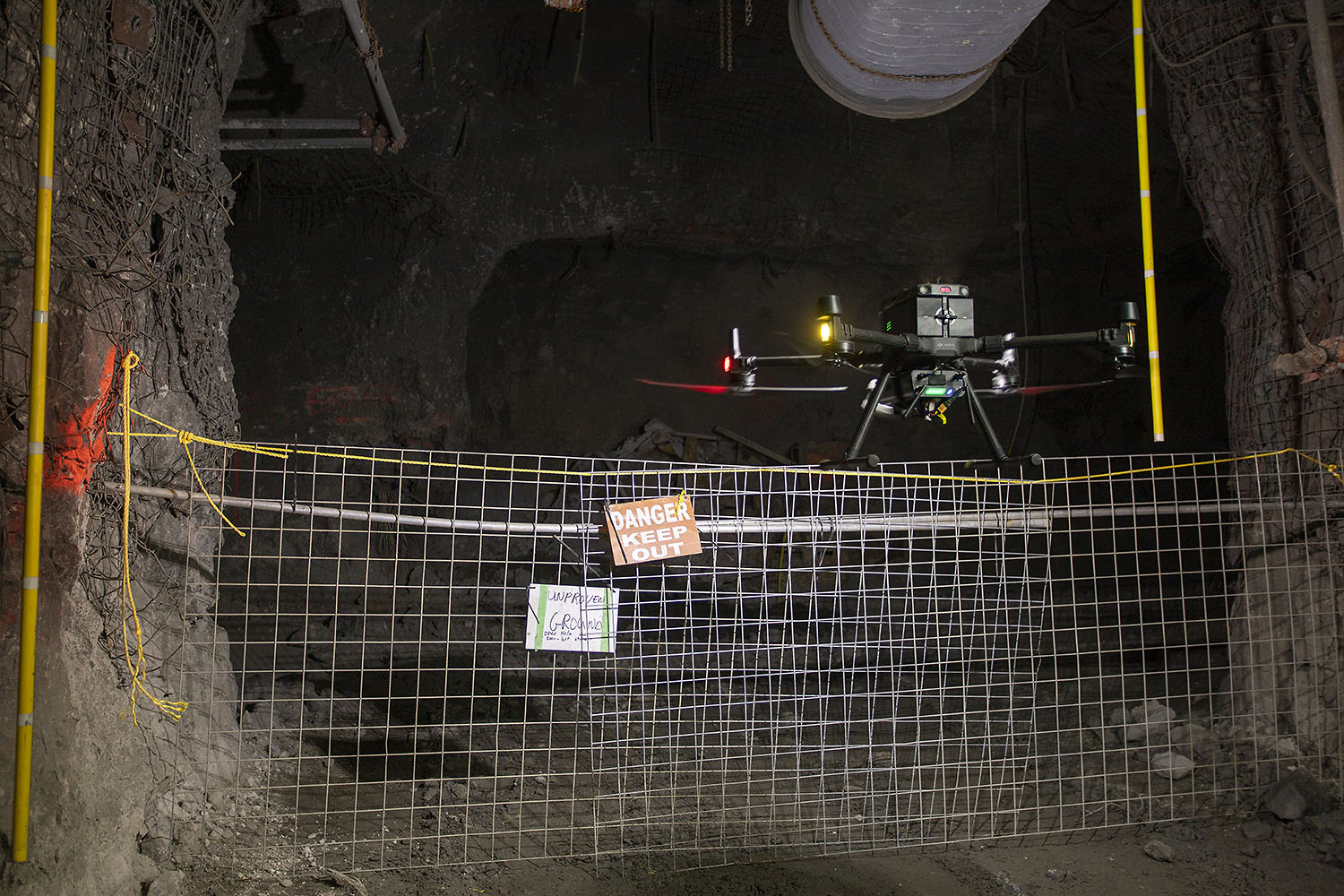 Drone flying past a Danger Keep Out sign marking unproven ground in a mine